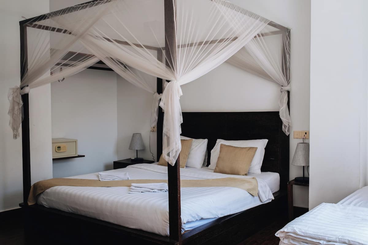 Una cama con dosel y cuatro columnas, con ropa de cama blanca y un cabecero de madera.