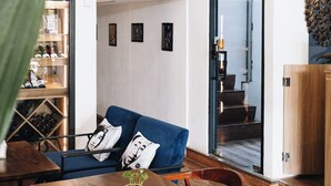A modern interior with a dining area featuring a wooden table and chairs, a blue sofa with decorative pillows, and a black sign above. - Suite Home Boutique Hotel (Phnom Penh)