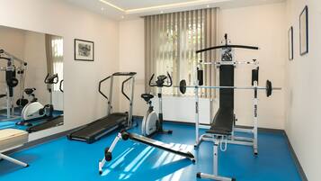 A modern gym with cardio machines, a weight bench, and a mirrored wall.