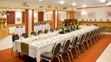 Una larga mesa de banquete dispuesta para un evento formal, con sillas colocadas a ambos lados.