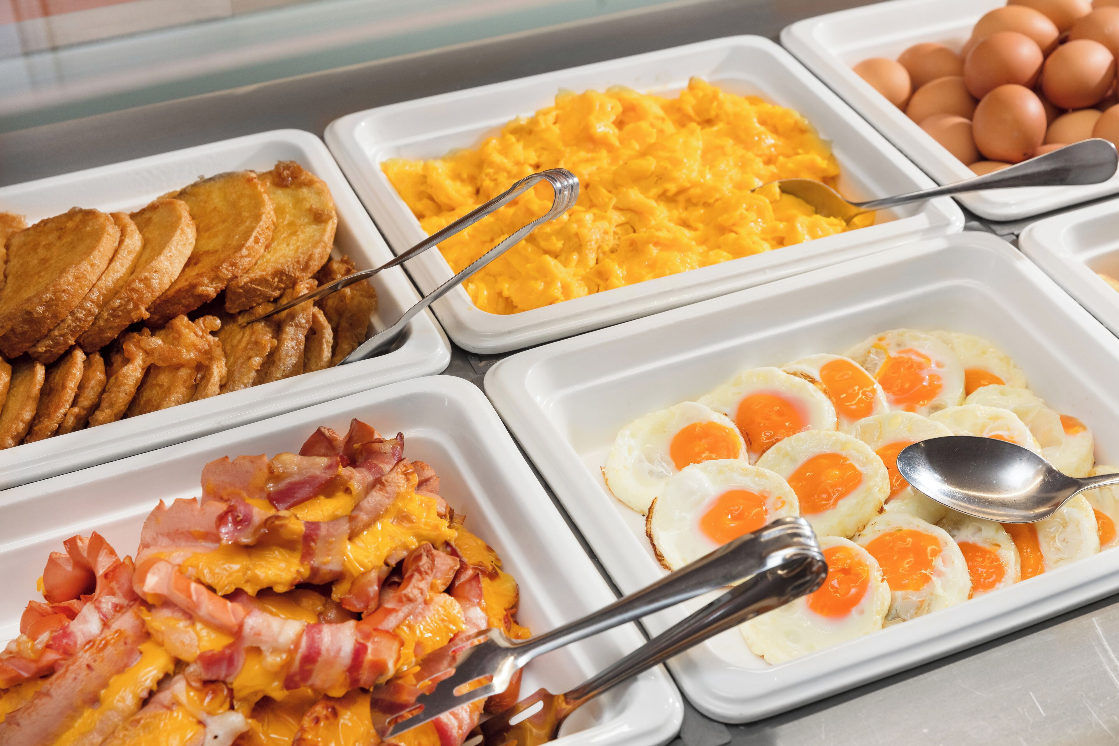 A breakfast buffet with various food options including eggs, bacon, scrambled eggs, and toast.