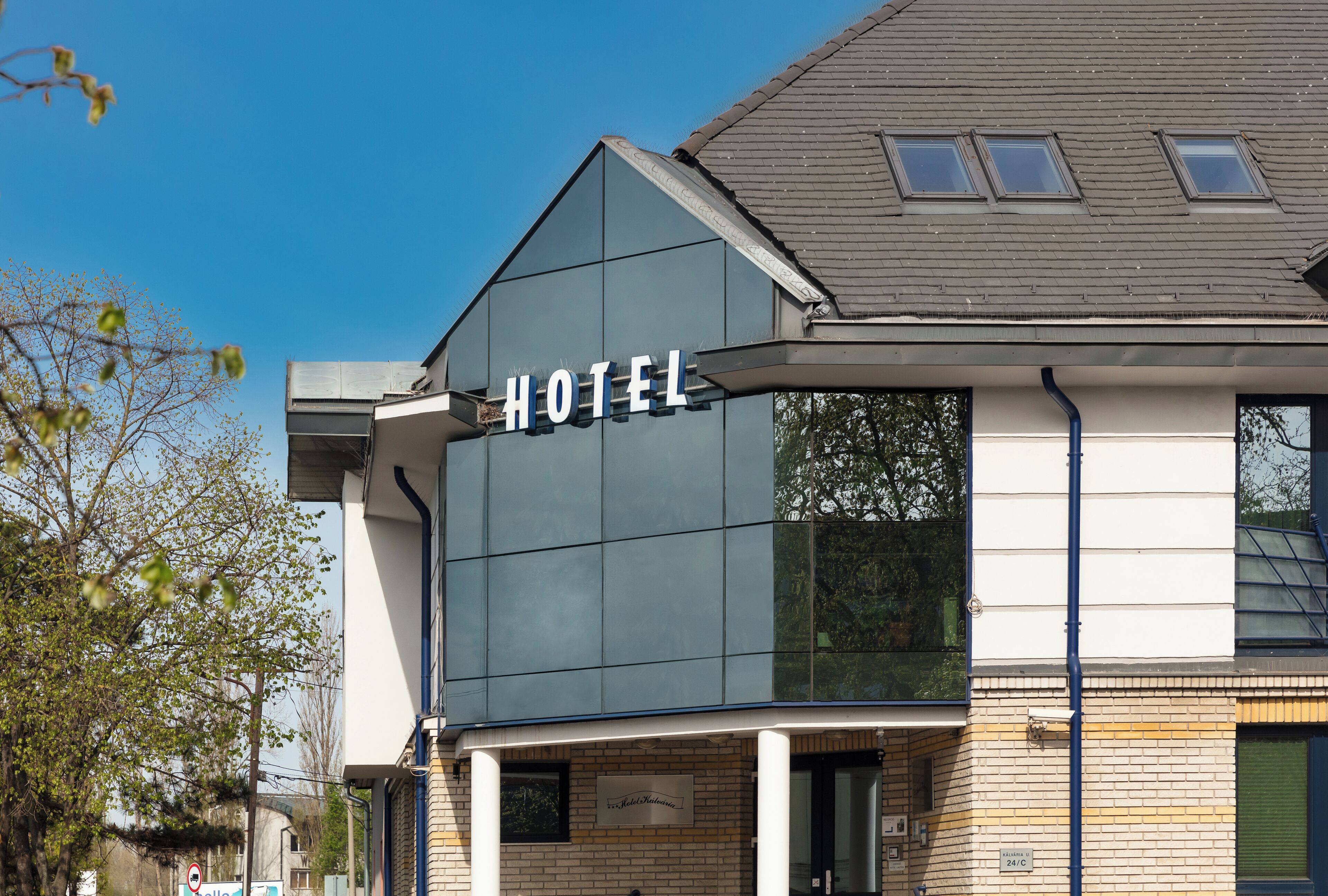 A modern hotel with a prominent "HOTEL" sign, a brick facade, and a flat roof with skylights.