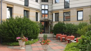 A courtyard with outdoor seating and potted plants. - Hotel Kálvária (Gyor)