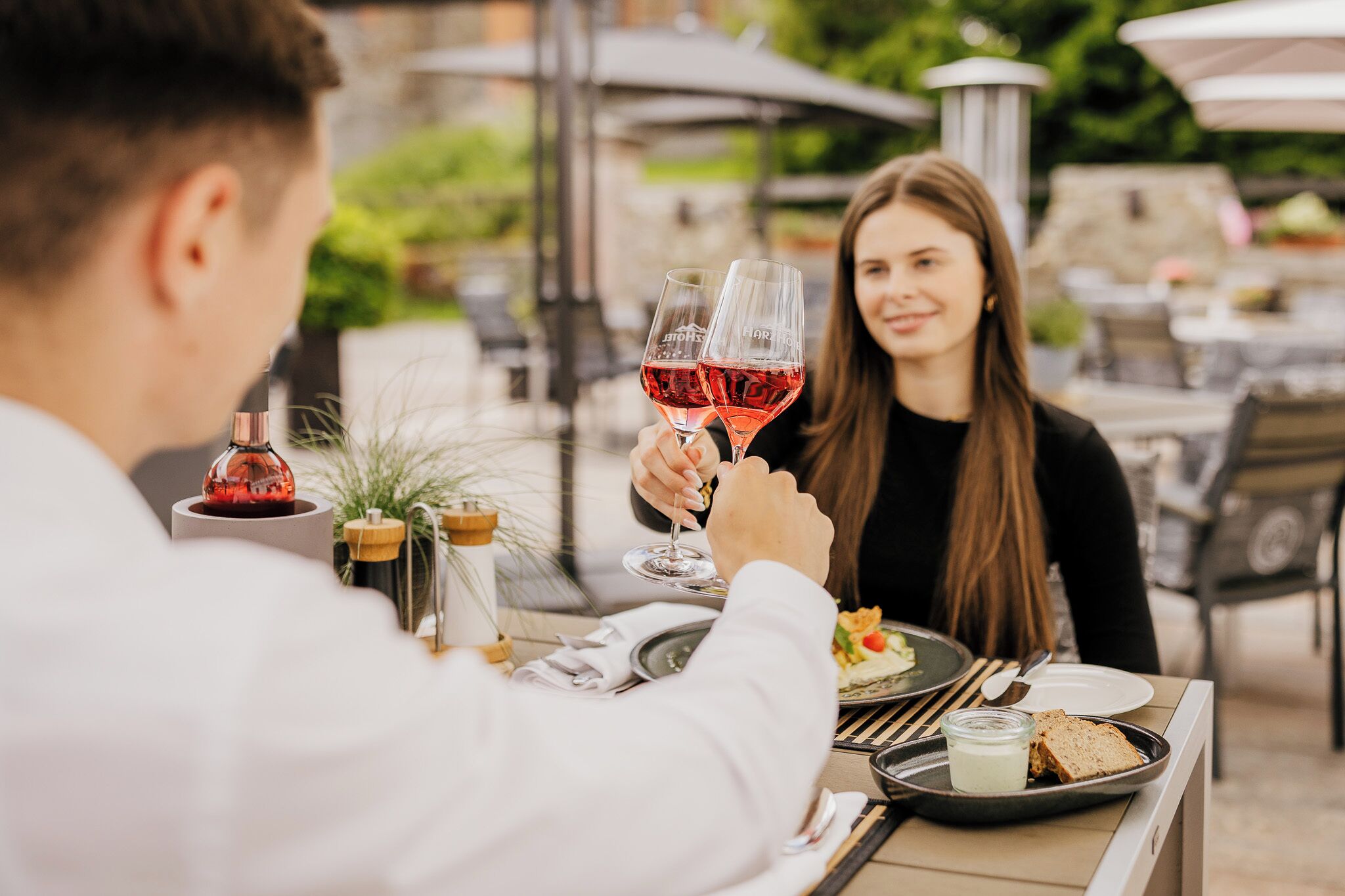 A dining table with a bottle of red wine, a glass, and a plate with food.