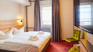 Ein Hotelzimmer mit Bett, Fernseher, Schreibtisch und Stuhl.