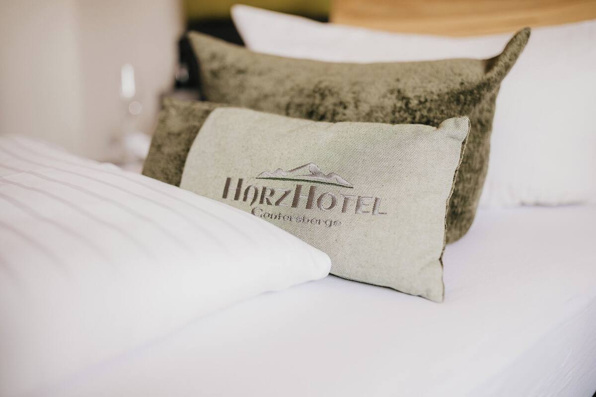 A bed with a pillow labeled "Horizon Hotel" and a textured pillow.