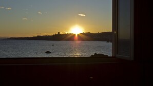 A sunset over a body of water with a distant city skyline. - Oasis (Aci Castello)