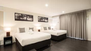 A hotel room with two beds, each with a nightstand and lamp, a wooden coffee table, and a magazine on it.