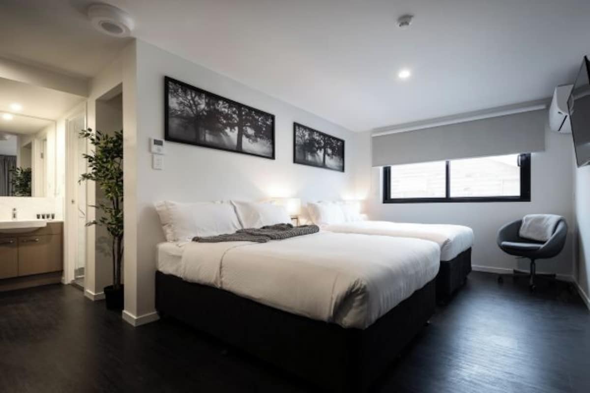 A modern bedroom with a large bed, bedside tables, a chair, and a window.