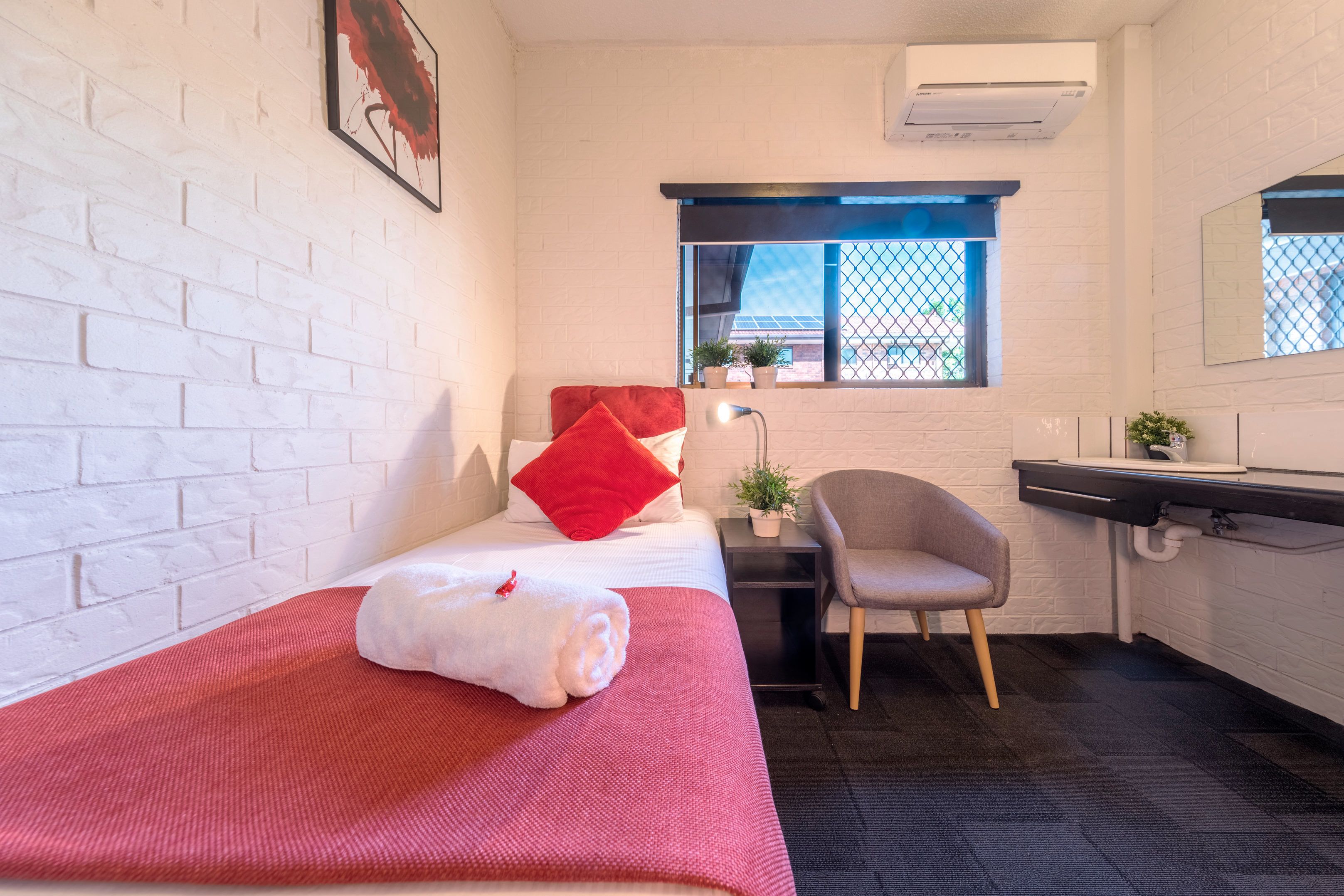 Una habitación pequeña y limpia con una cama, un escritorio, una silla y una ventana.
