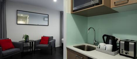 A modern kitchen with a microwave, toaster, and sink. There is a small dining area with two chairs and a table.
