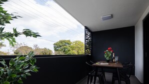 A balcony with a table, chairs, a potted plant, and a bottle of champagne.