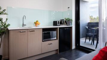 A modern kitchen with a microwave, toaster, and sink. There is a dining area with a table and chairs.