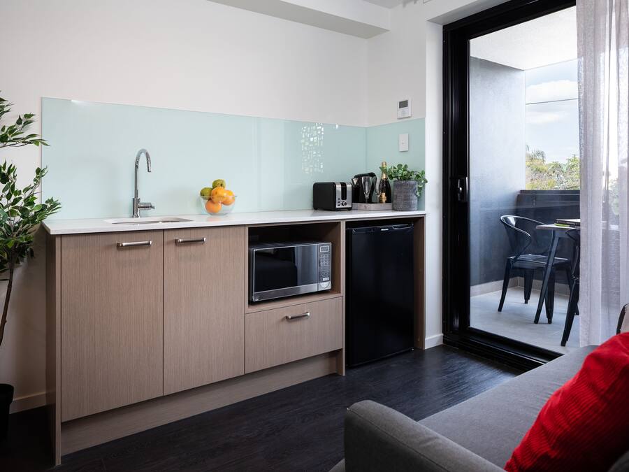 A modern kitchen with a microwave, toaster, and sink. There is a dining area with a table and chairs.