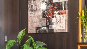A room with a brown leather armchair, a large green potted plant, and a wall with abstract art.
