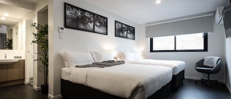 A modern bedroom with a large bed, bedside tables, a potted plant, and a window.