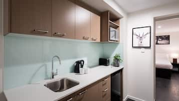 Una cocina moderna con un lavamanos de acero inoxidable, armarios de madera y un microondas.