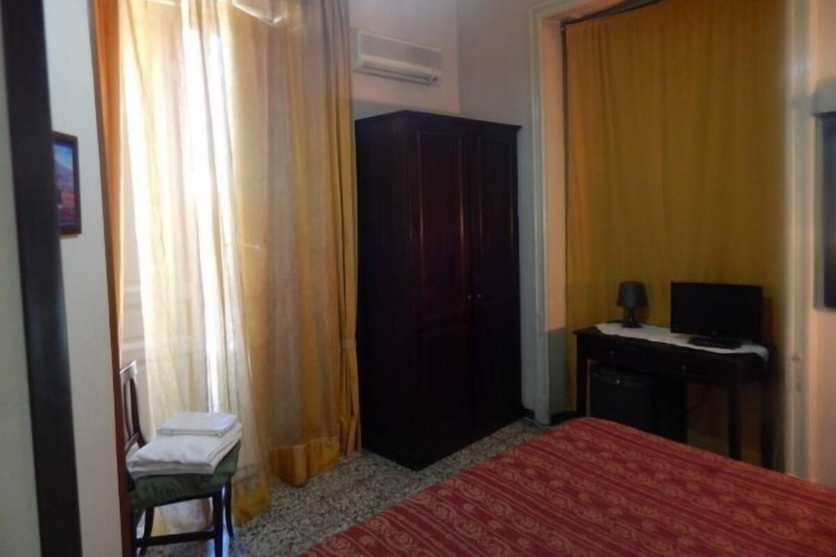 Una habitación de hotel con una cama, un escritorio con computadora, un armario y una silla.