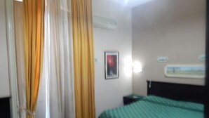 A hotel room with a bed, a nightstand, a wall-mounted air conditioner, and a window with a view. - Rooms 20 Settembre (Catania)