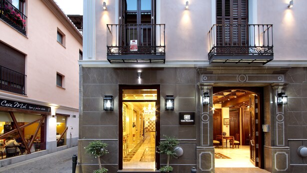 A hotel entrance with a double door, a sign indicating 'Casa Palacete 1822', and a small tree in front. - Casa Palacete 1822 (Granada)