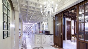A hallway with a patterned floor, a central island with a counter, and a chandelier. - Casa Palacete 1822 (Granada)