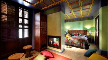 Una habitación con una cama grande, una chimenea, una puerta de madera y una ventana con persianas.