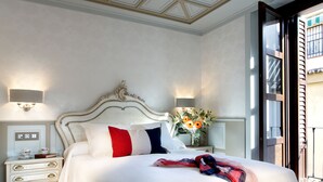A bedroom with a large bed, bedside tables, a nightstand, and a view of the outside. - Casa Palacete 1822 (Granada)