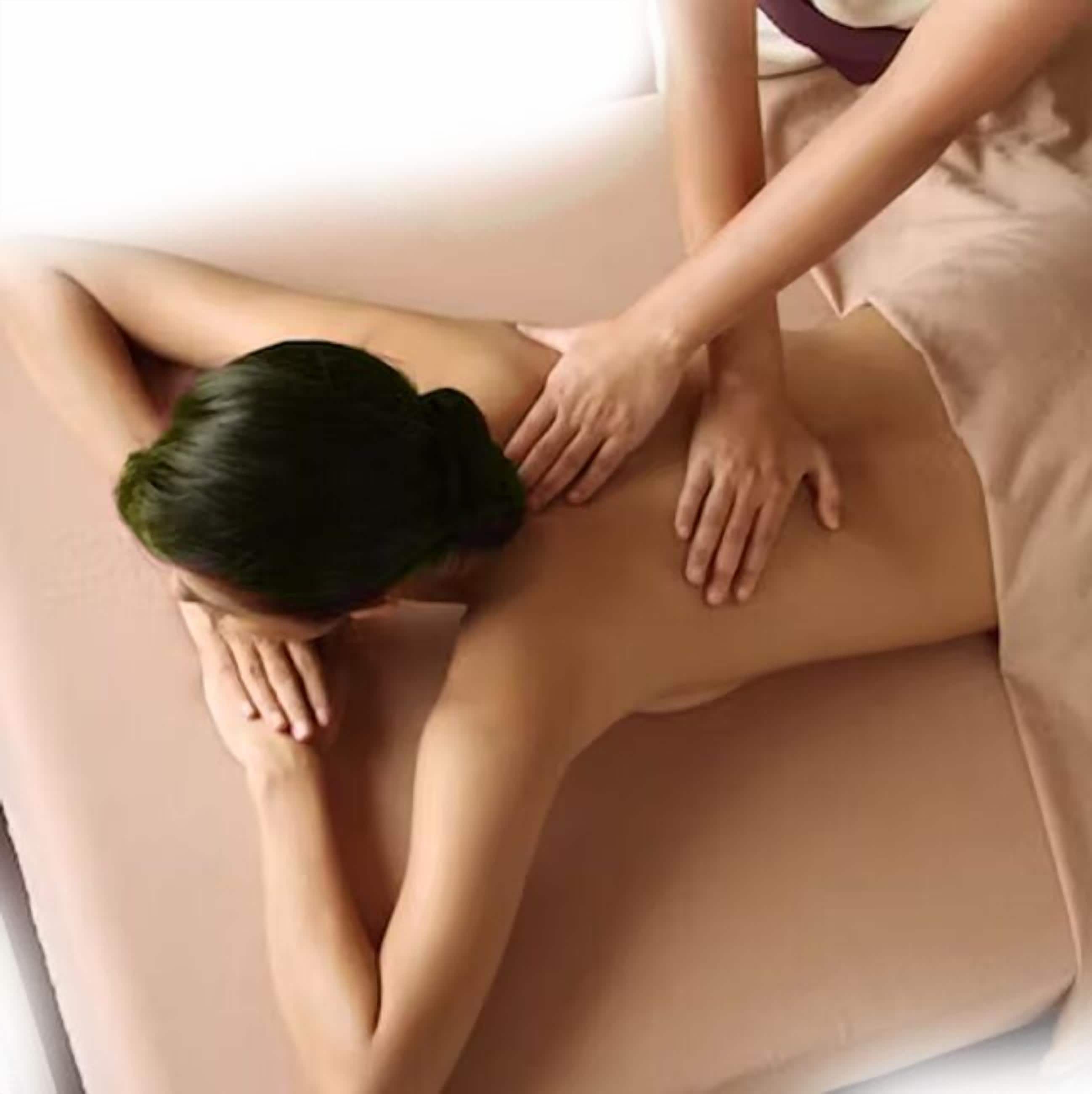 Uma pessoa recebendo uma massagem nas costas em uma mesa de massagem bege.