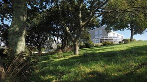 A grassy area with trees and a modern building in the background. - Belvédère Hôtel (Brest)