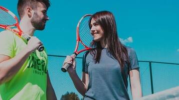Two people holding tennis rackets on a tennis court.