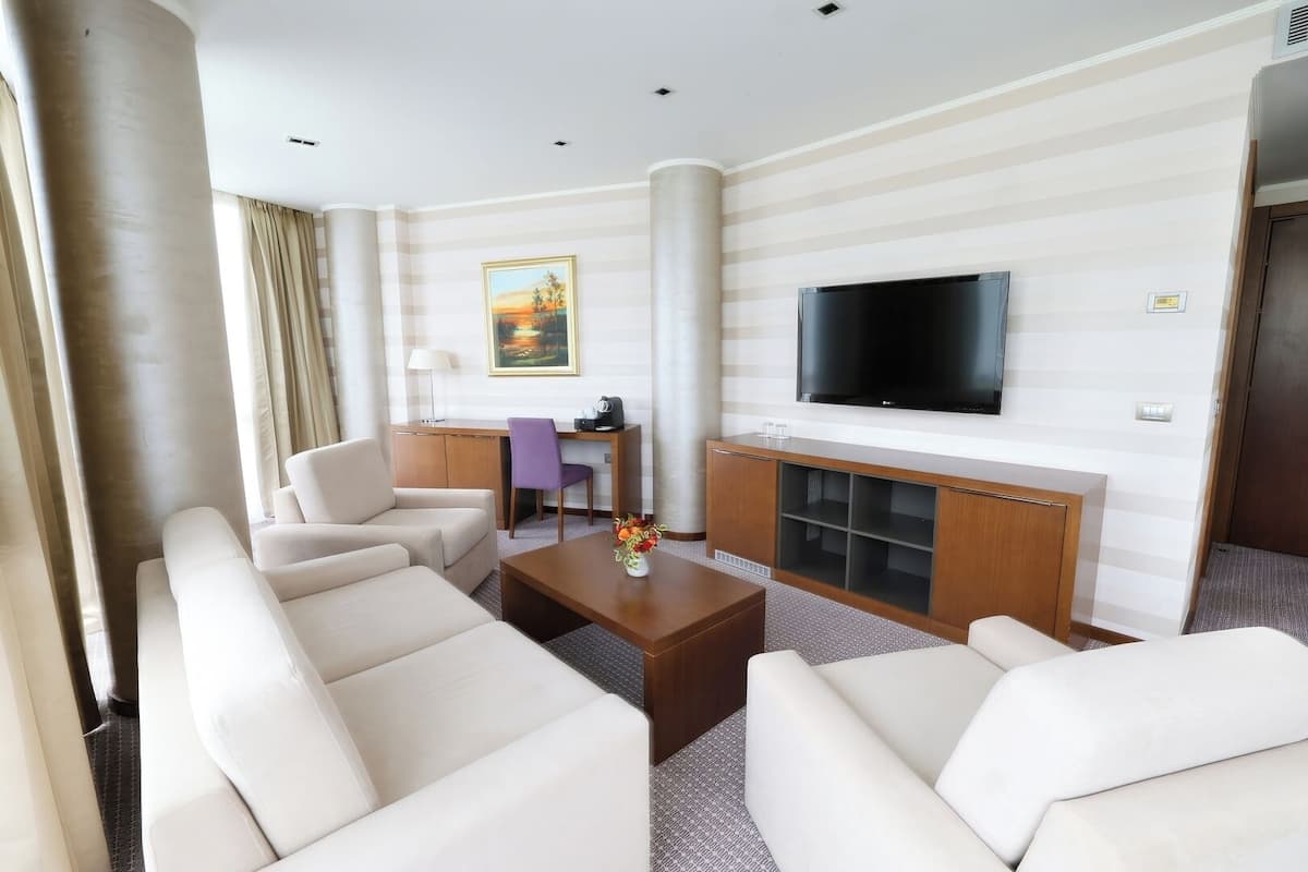 Ein Hotelzimmer mit einer Sitzecke, ausgestattet mit zwei Sofas, einem Couchtisch und einem an der Wand montierten Fernseher.