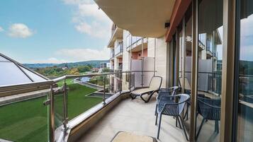 A balcony with a view of a green lawn and buildings in the distance.