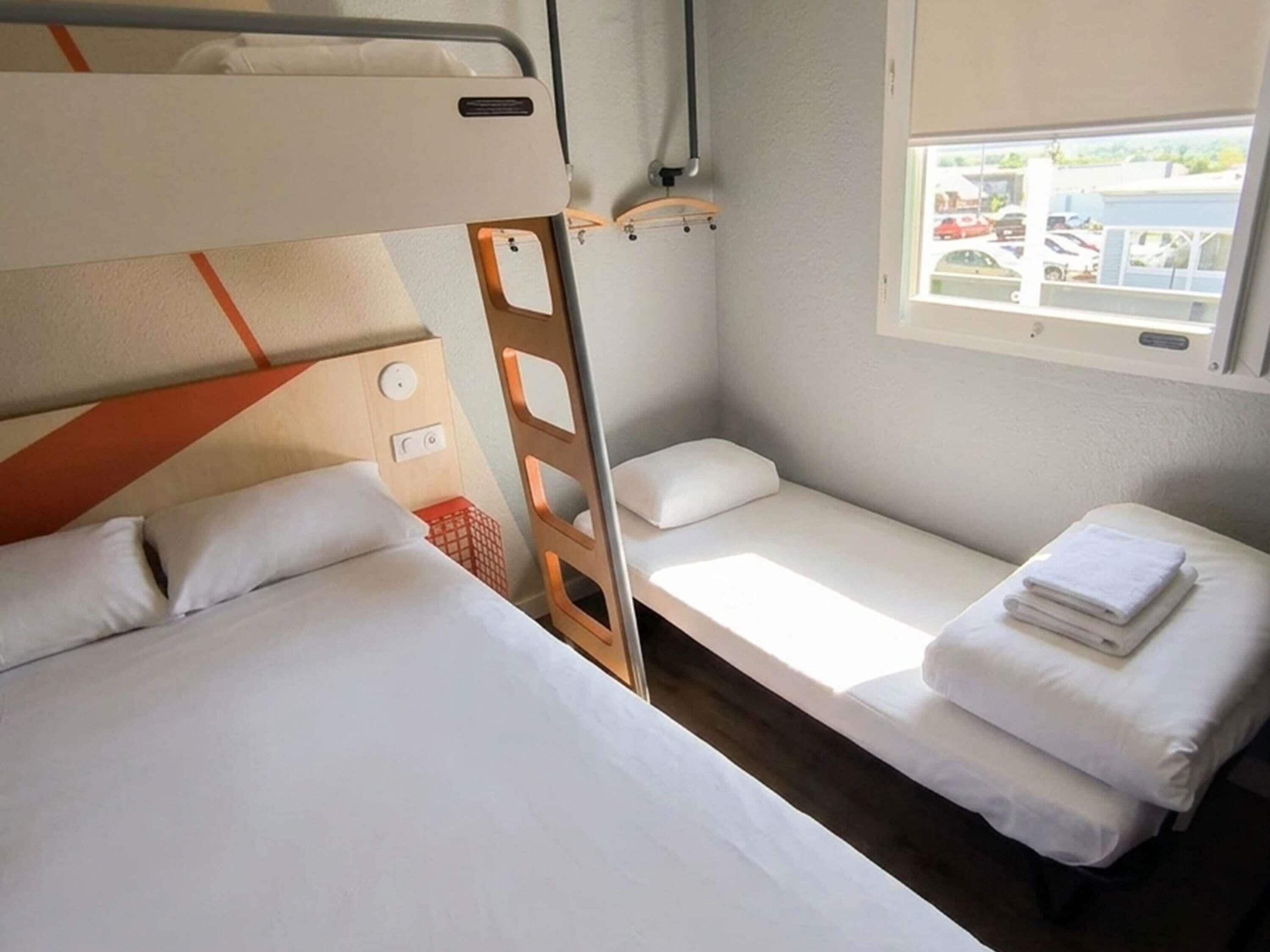 Habitación con literas, una mesita de noche y un pequeño estante.