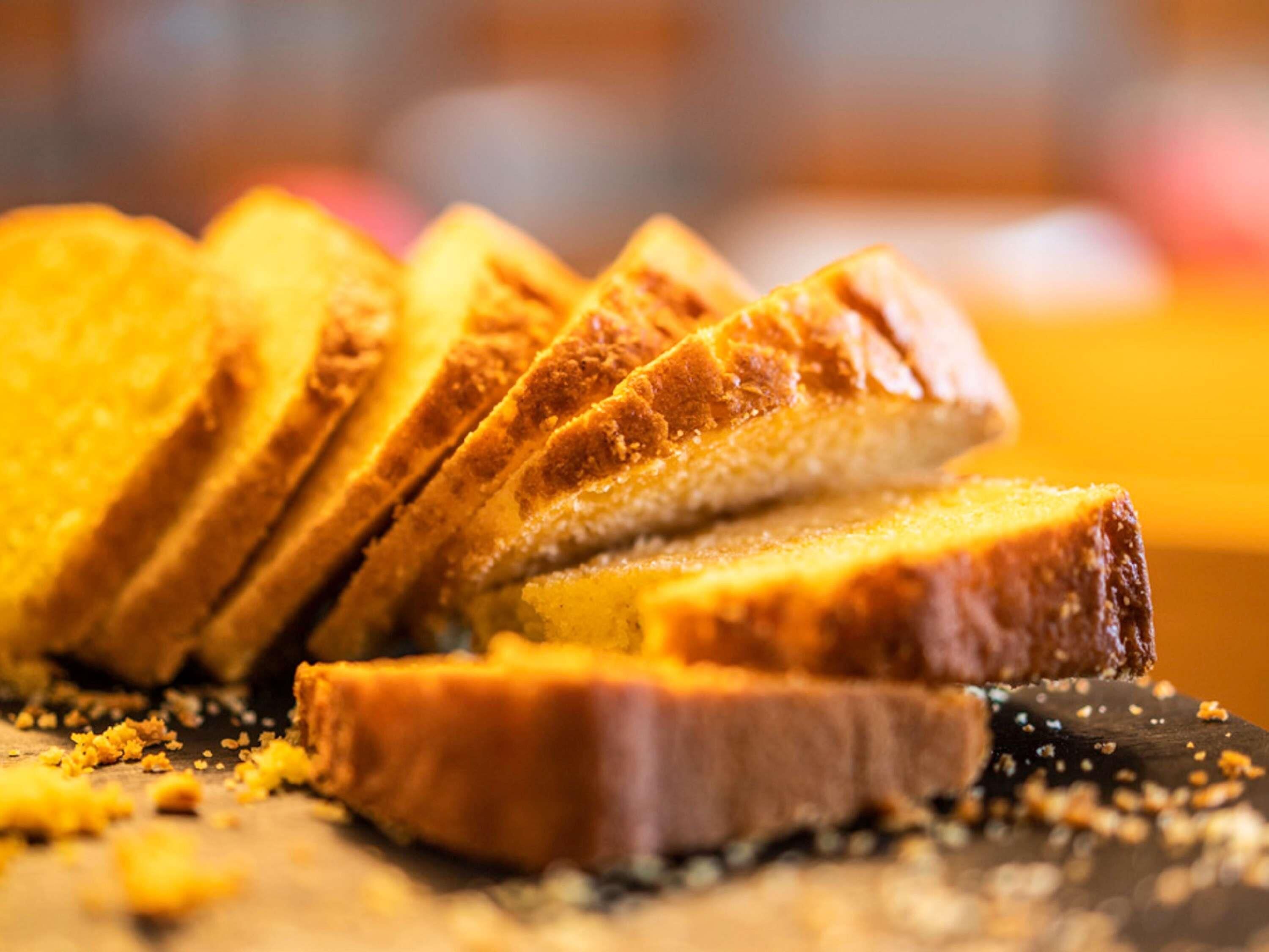 A close-up of sliced toast with crumbs on a wooden surface.