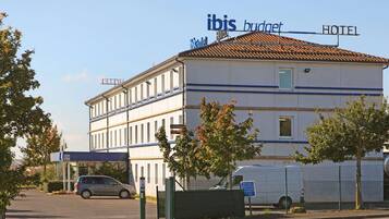 A two-story building with a sign for 'ibis budget HOTEL' and a 'CANAL' sign on the ground floor.