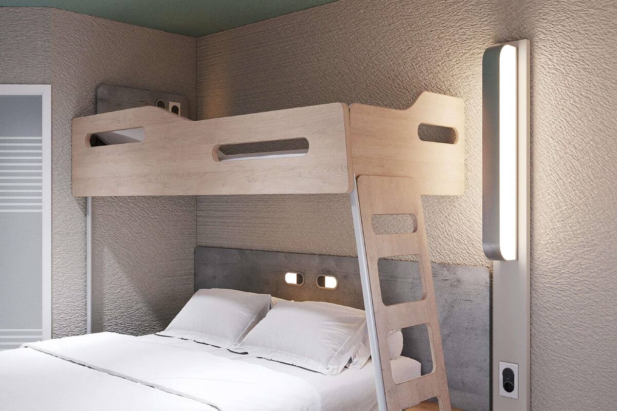 A bunk bed with a ladder, a bedside table, and a wall-mounted light fixture.