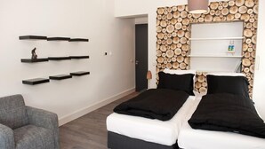 A modern bedroom with a bed, two bedside tables, a chair, and a wall decorated with wooden logs. - B&B Erve Fakkert (Rossum)