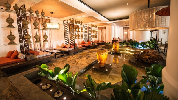 Un vestíbulo espacioso con zonas de estar, lámparas decorativas y una fuente central.