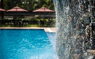 Una piscina al aire libre, sombrillas, sillones reclinables de piscina