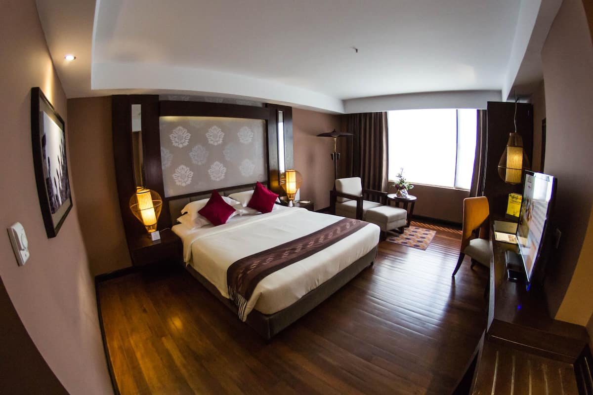 Ein Hotelzimmer mit einem großen Bett, einem Schreibtisch, einem Sessel und einem Fernseher.