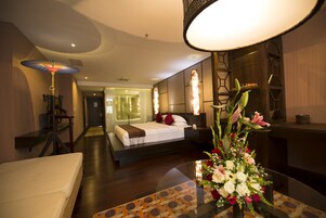 Una habitación de hotel con cama, mesita de noche y un jarrón de flores.