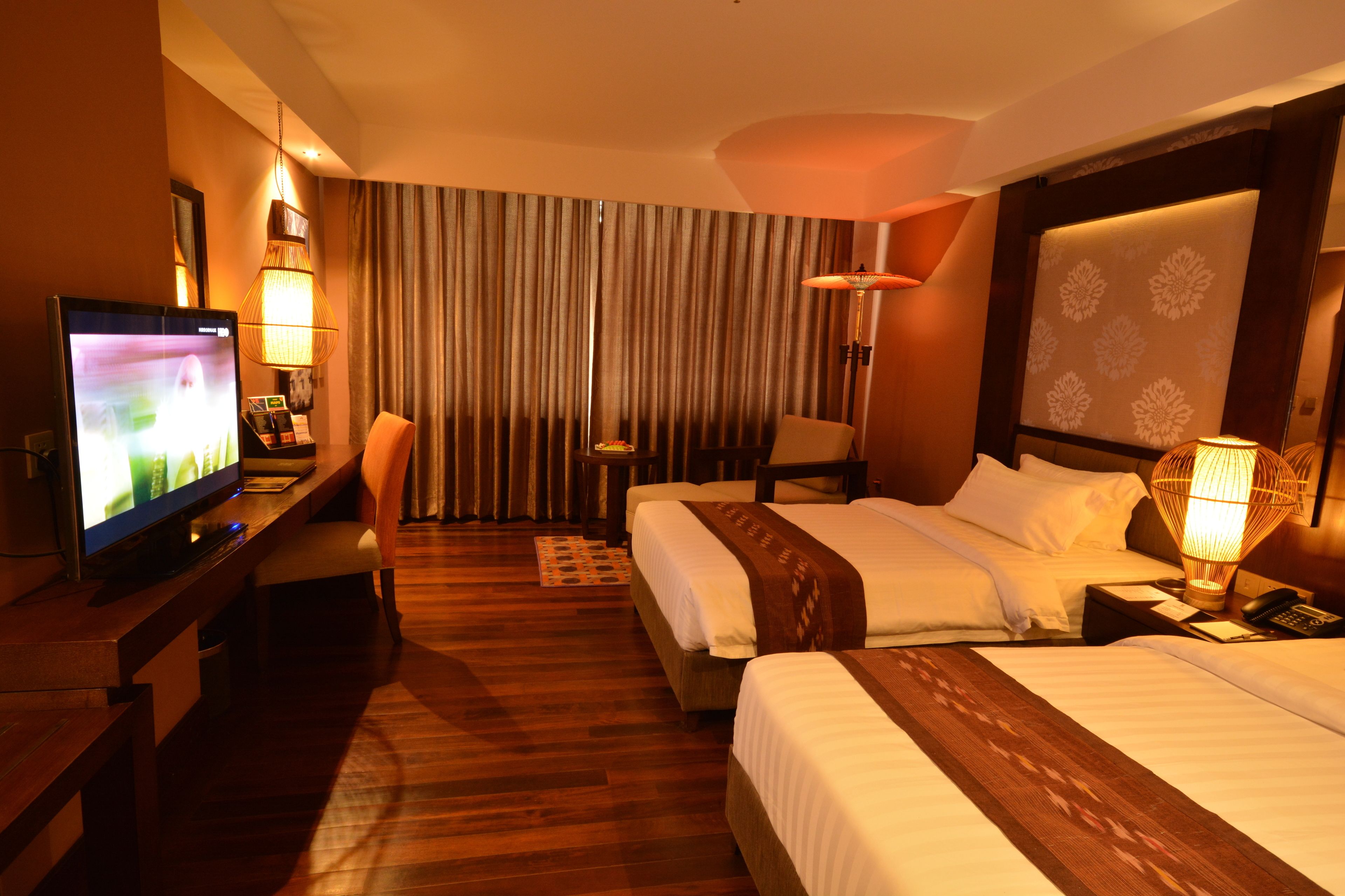A hotel room with a television, two beds, a desk, and a chair.