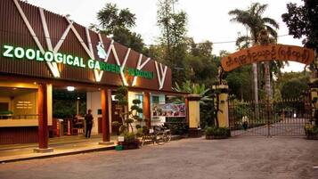 A zoological garden entrance with a signboard and a gated entrance.