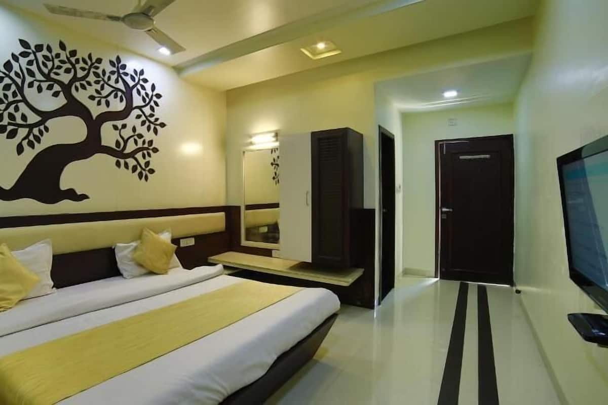 A hotel room with a bed, a TV, a wardrobe, and a mirror.