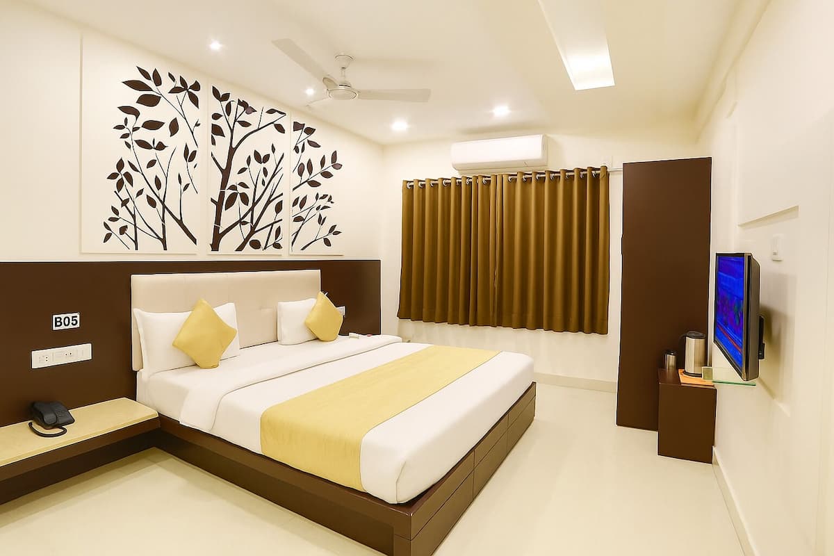 A modern hotel room with a large bed, a flat-screen TV, a ceiling fan, and a wall-mounted air conditioner.