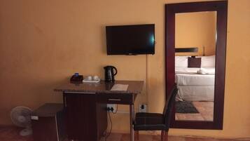 Habitación de hotel con escritorio, silla, televisor y cama.