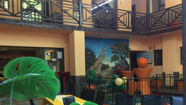 A dining area with tables and chairs, a mural of giraffes, and a balcony with railings. - Sgegede Guest House (Pretoria)