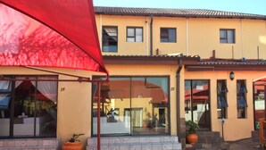 A building with numbered windows, a red awning, and potted plants. - Sgegede Guest House (Pretoria)