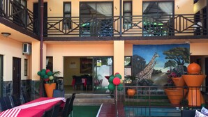 A hotel lobby with a dining area, a painting of a giraffe, and a balcony with a railing. - Sgegede Guest House (Pretoria)
