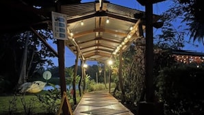 An outdoor covered walkway with a tiled floor, leading to a building. - Lirio Lodge (Pacuarito)